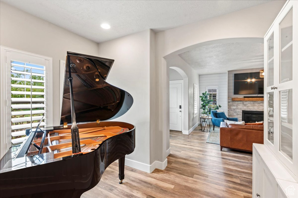 Interior space featuring light wood-style floors, arched walkways, a textured ceiling, and baseboards