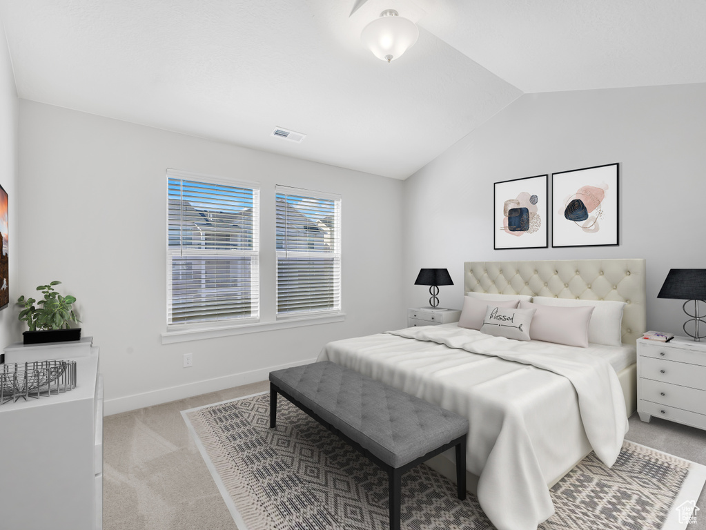Bedroom featuring baseboards, visible vents, light colored carpet, and vaulted ceiling
