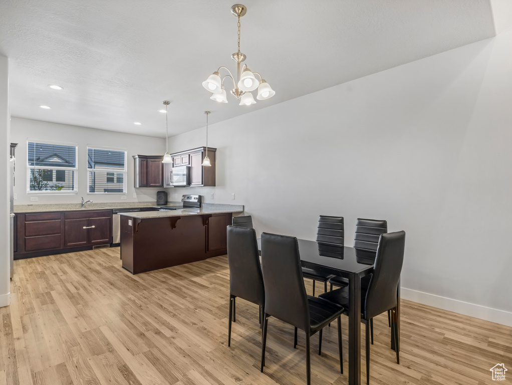 Dining space featuring an inviting chandelier, light wood-style flooring, baseboards, and recessed lighting
