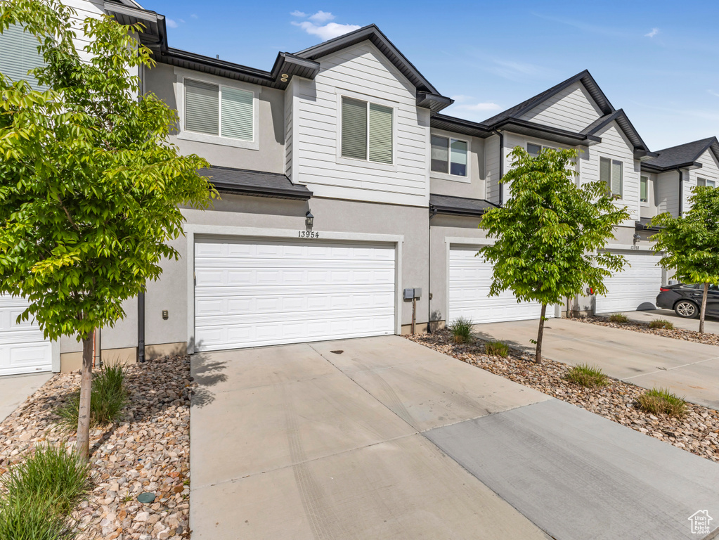 Townhome / multi-family property featuring an attached garage, stucco siding, and driveway