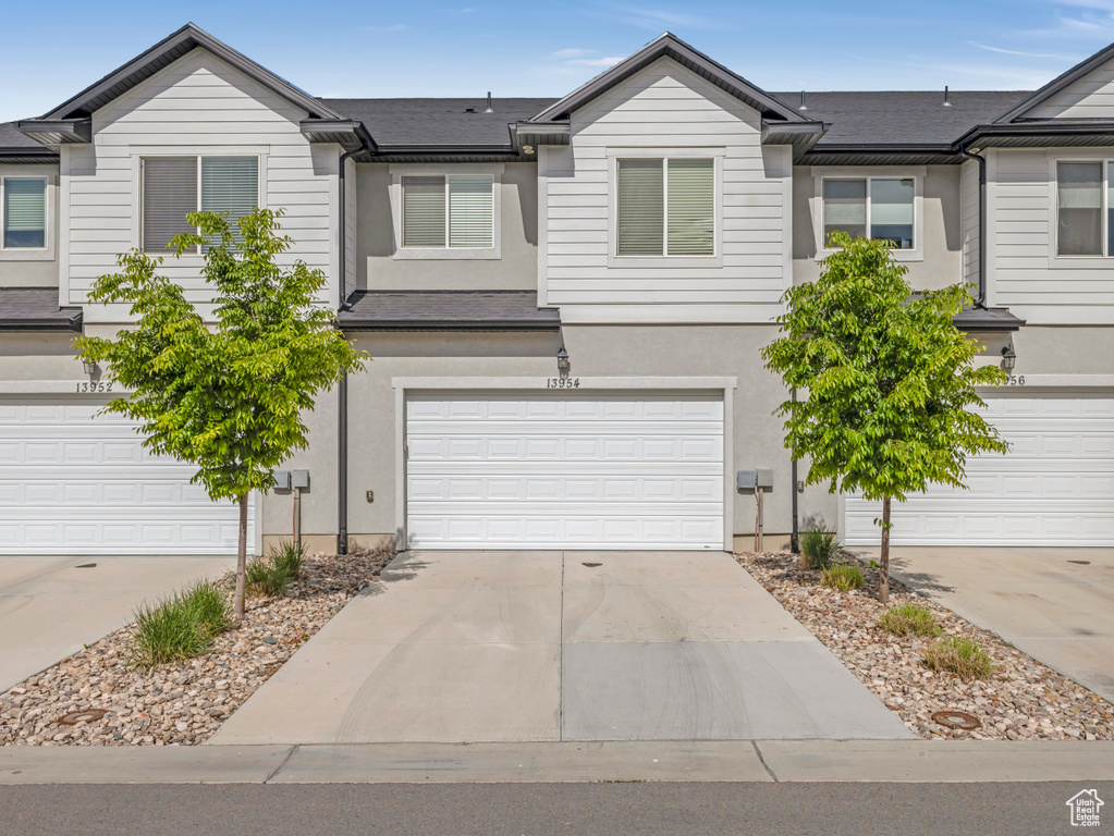View of property with driveway, stucco siding, and a garage