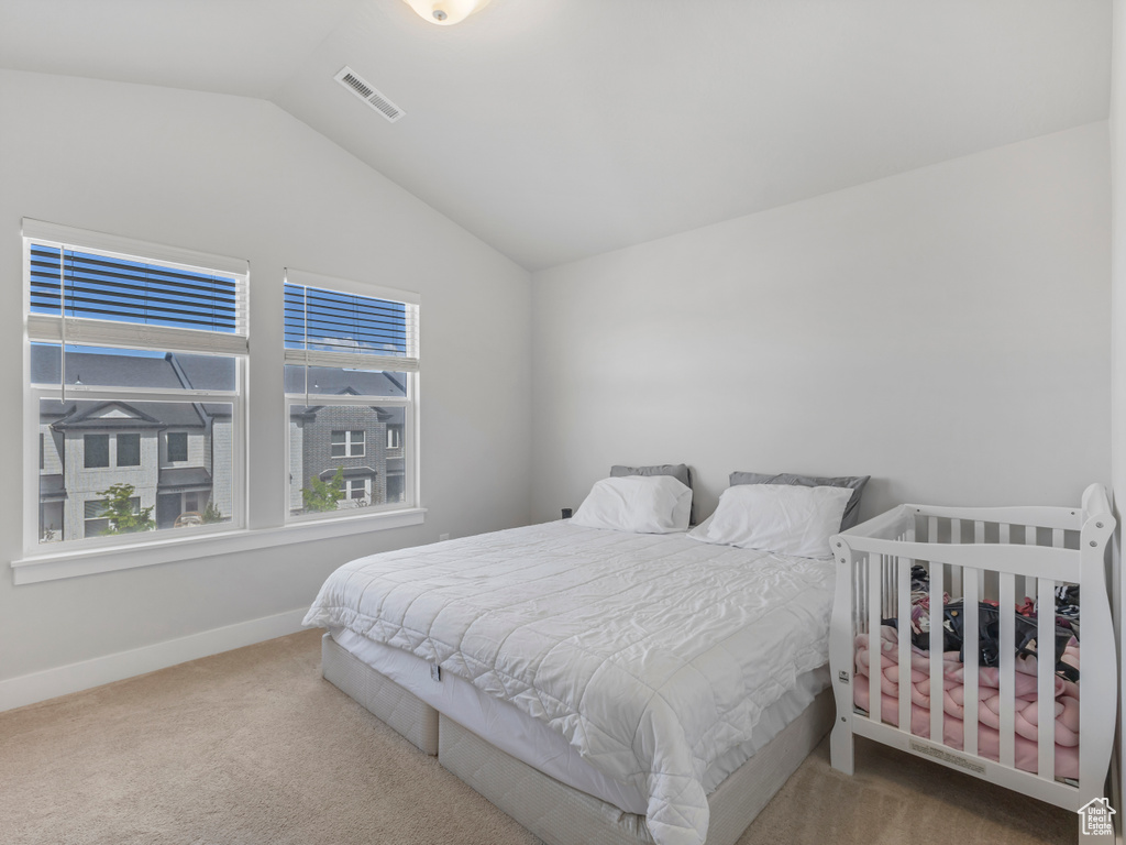 Carpeted bedroom featuring lofted ceiling, baseboards, and visible vents