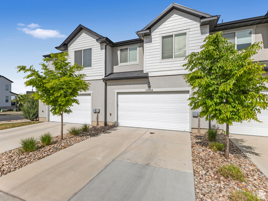 View of front of property with concrete driveway, an attached garage, and stucco siding