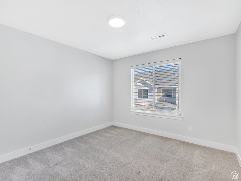 Spare room with light colored carpet, baseboards, and visible vents