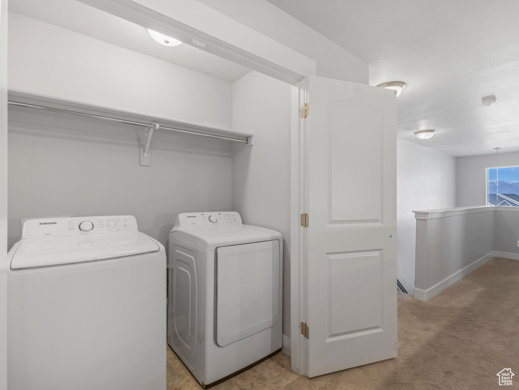 Laundry area featuring laundry area, light carpet, baseboards, and washing machine and dryer