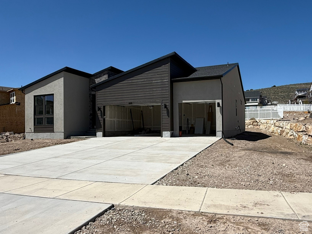 Modern home featuring driveway, an attached garage, and fence