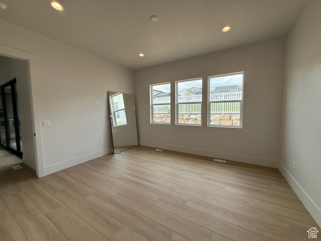 Empty room featuring light wood-style floors, baseboards, and recessed lighting