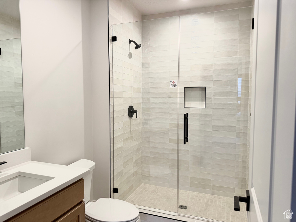 Full bath with toilet, vanity, and a stall shower