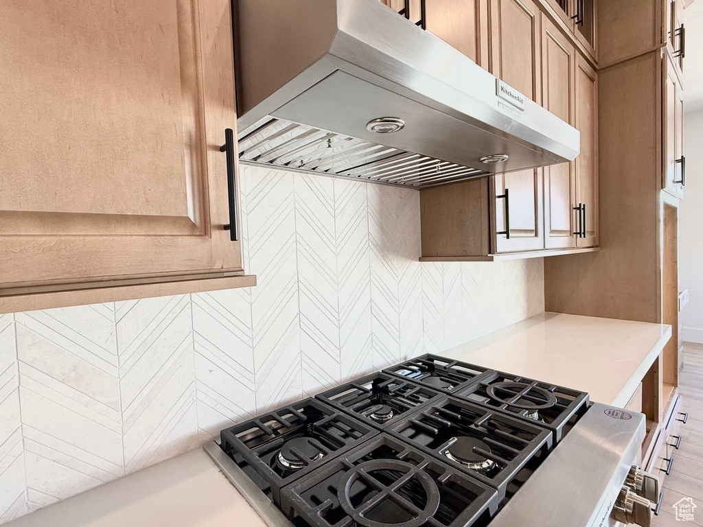 Kitchen with ventilation hood, light countertops, and tasteful backsplash