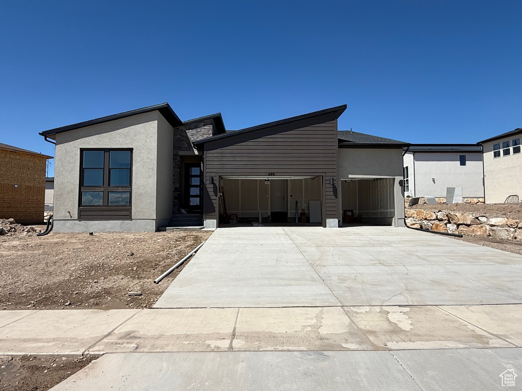 Modern home featuring a garage, concrete driveway, and stucco siding