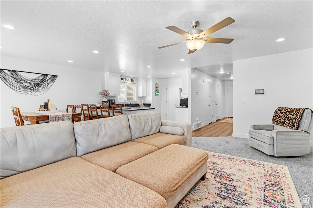 Living room featuring recessed lighting, ceiling fan, baseboards, light carpet, and a textured ceiling