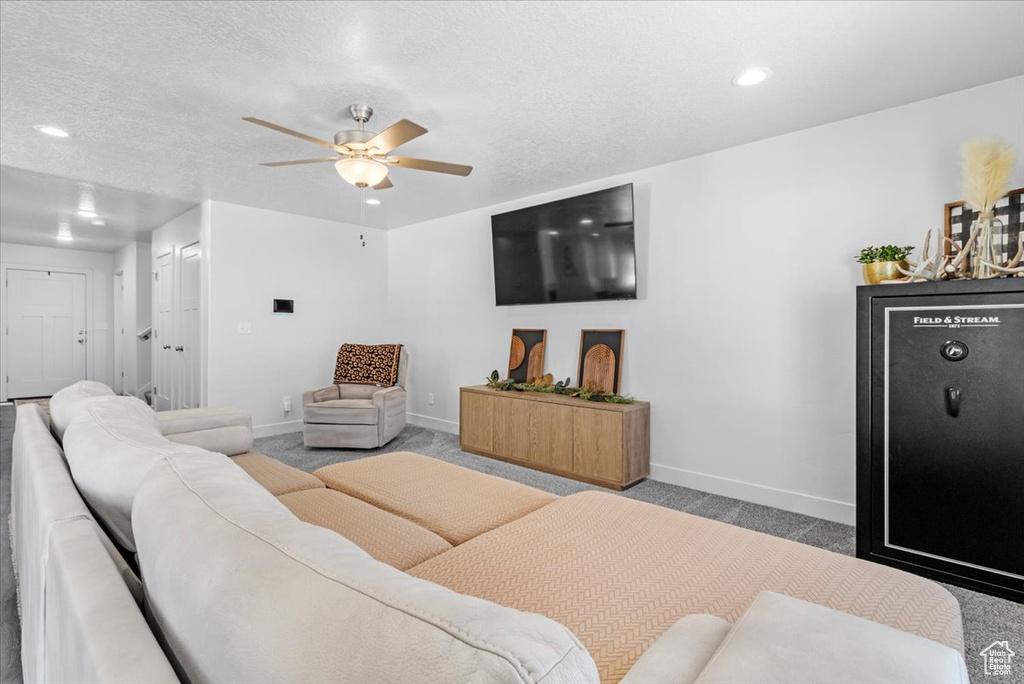Carpeted living area featuring baseboards, ceiling fan, and recessed lighting