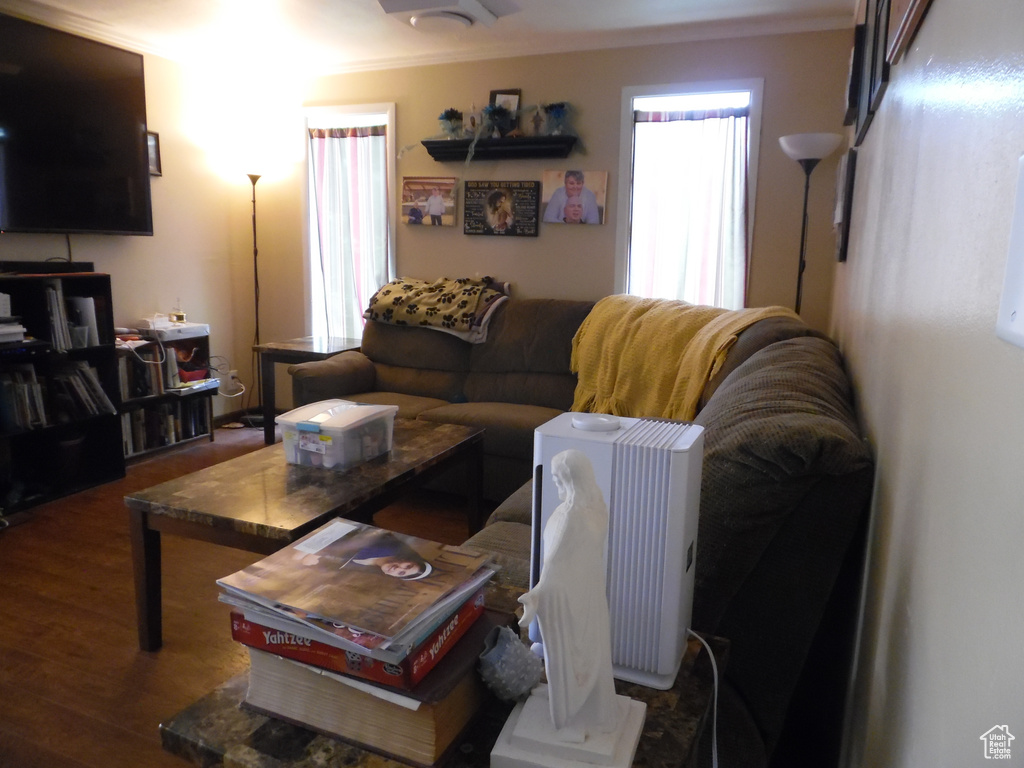 Living room with ornamental molding and wood finished floors