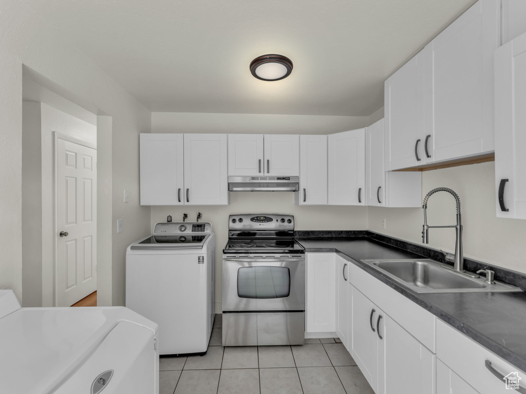 Kitchen with stainless steel electric range, a sink, under cabinet range hood, light tile patterned floors, and white cabinets