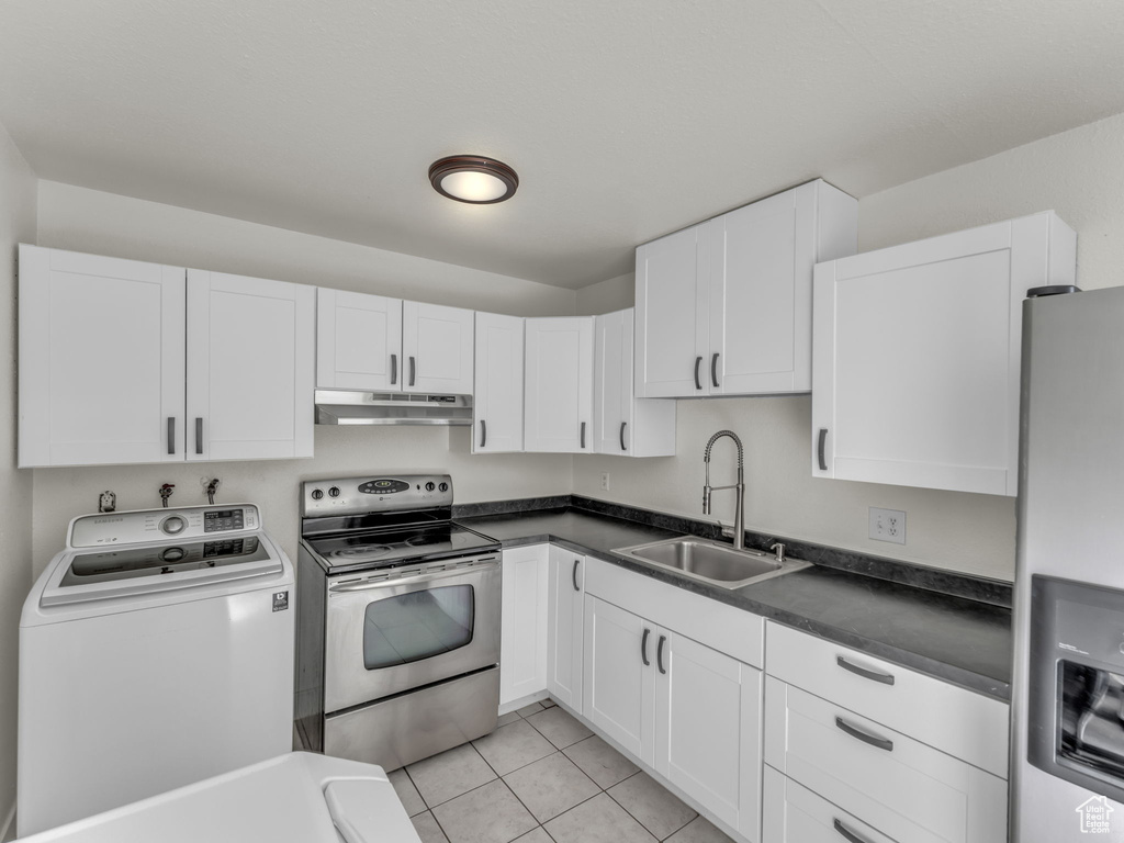 Kitchen with washer / dryer, stainless steel appliances, under cabinet range hood, a sink, and white cabinetry