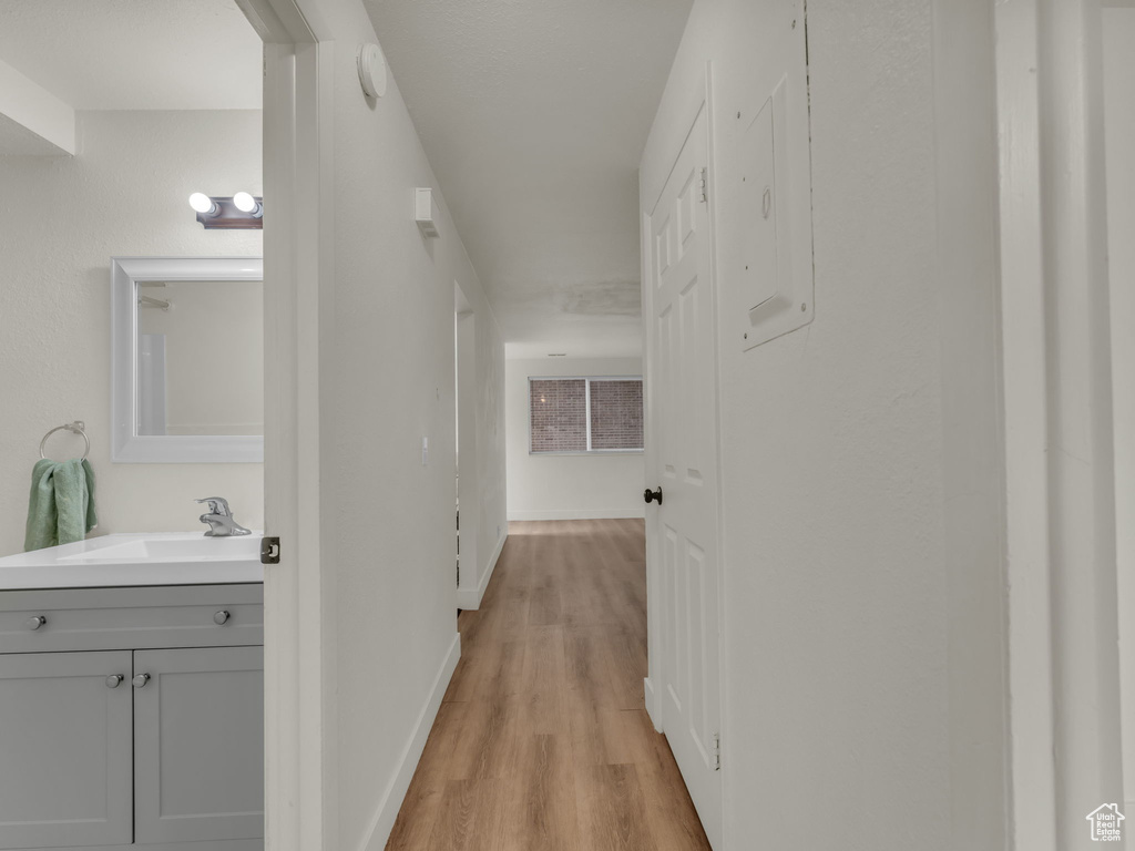 Hallway featuring a sink, light wood-style floors, and baseboards