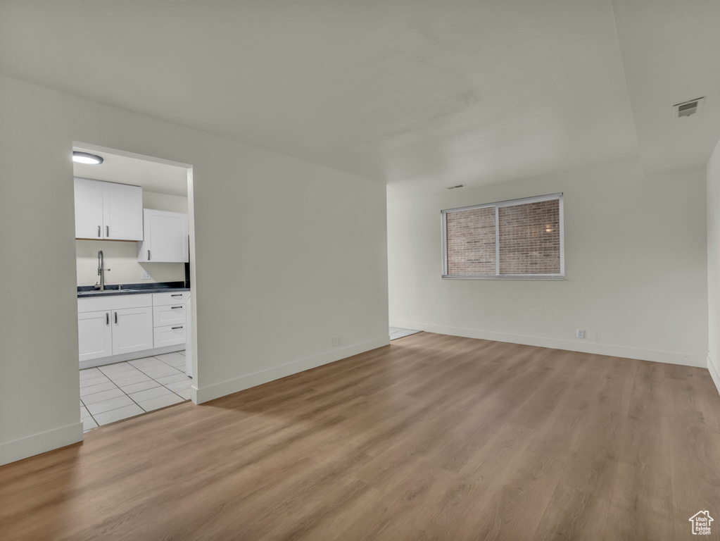 Spare room featuring light wood finished floors, a sink, and baseboards