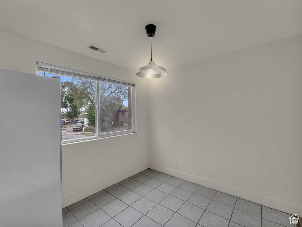 Unfurnished dining area with light tile patterned flooring and baseboards