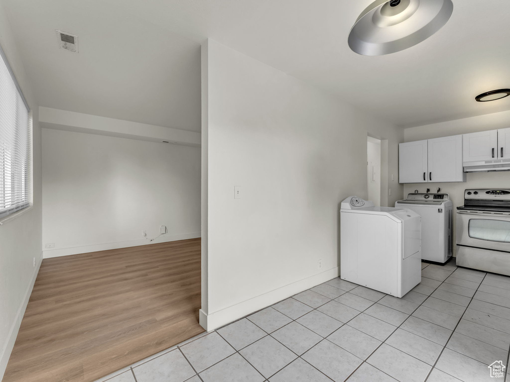 Laundry room with light tile patterned flooring, baseboards, and washing machine and clothes dryer