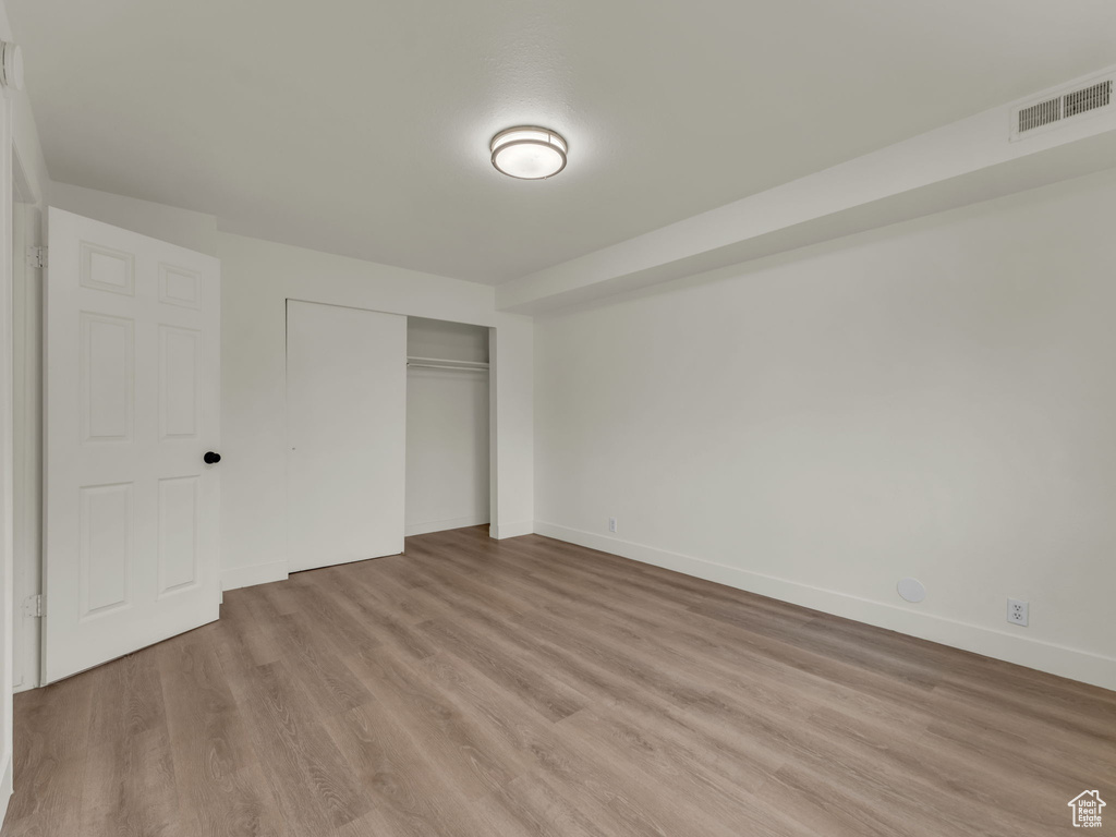 Unfurnished bedroom with light wood finished floors, a closet, and baseboards