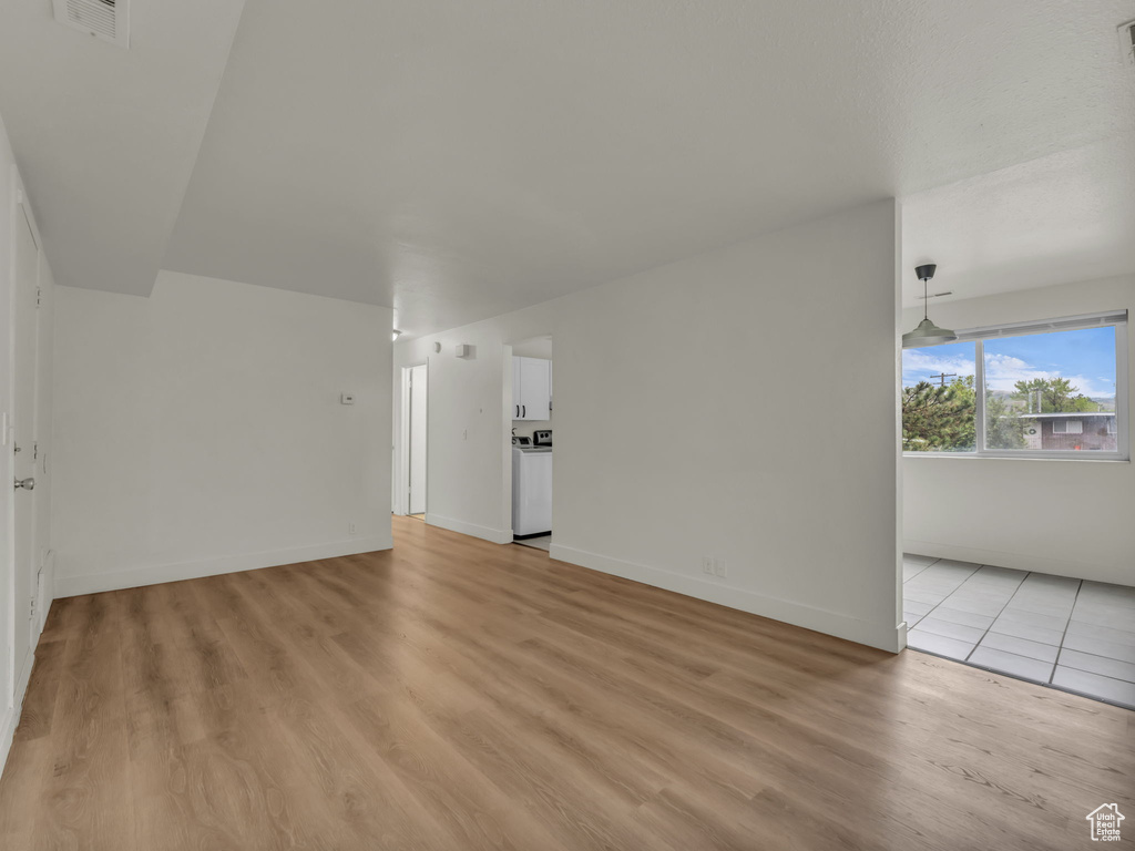 Unfurnished living room with light wood-style floors and baseboards