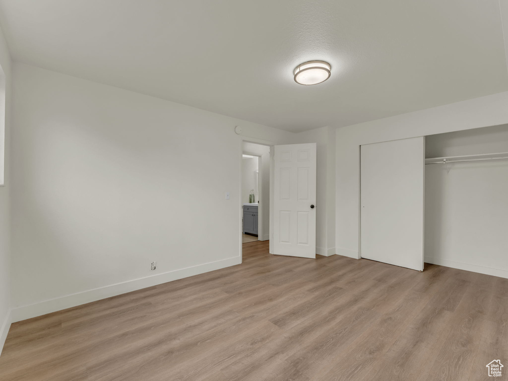 Unfurnished bedroom with light wood-style flooring, a closet, and baseboards