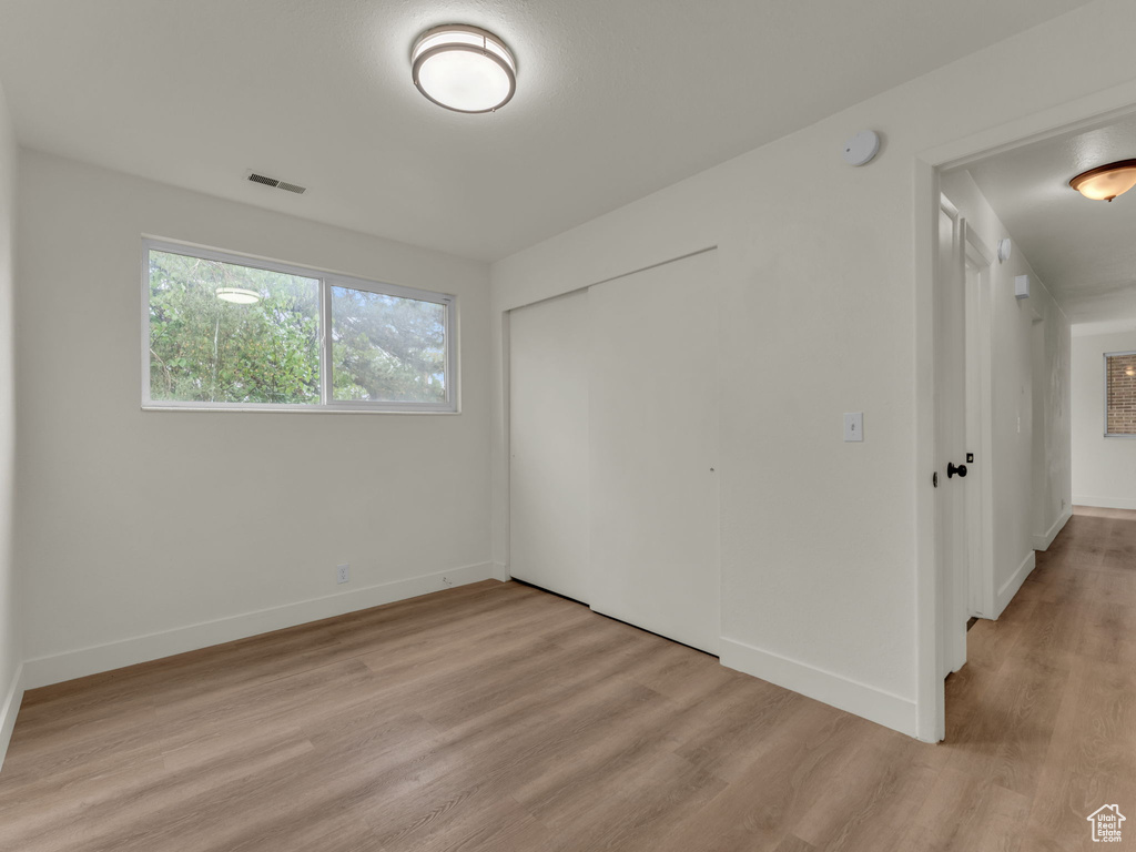 Unfurnished bedroom featuring light wood finished floors, a closet, and baseboards