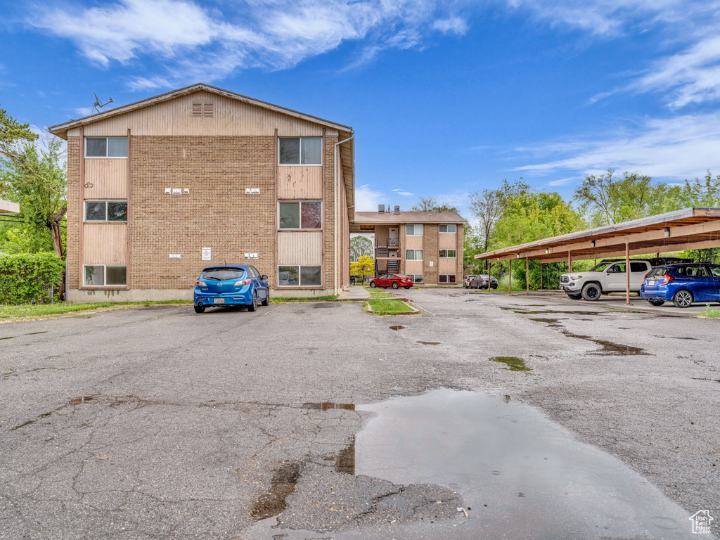 View of property featuring covered and uncovered parking