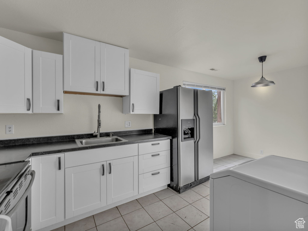 Kitchen with stainless steel appliances, a sink, white cabinetry, washer / clothes dryer, and hanging light fixtures