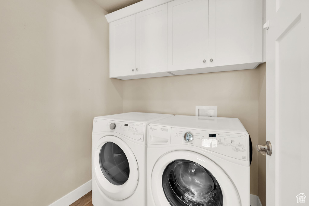 Clothes washing area with cabinet space, washer and dryer, and baseboards