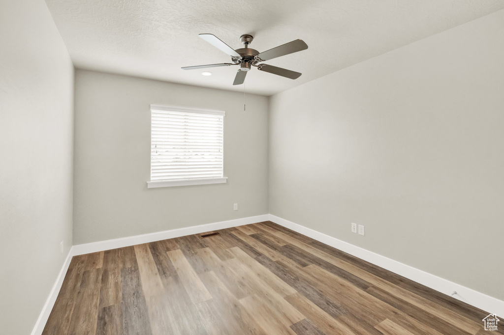 Spare room with wood finished floors, baseboards, and a ceiling fan