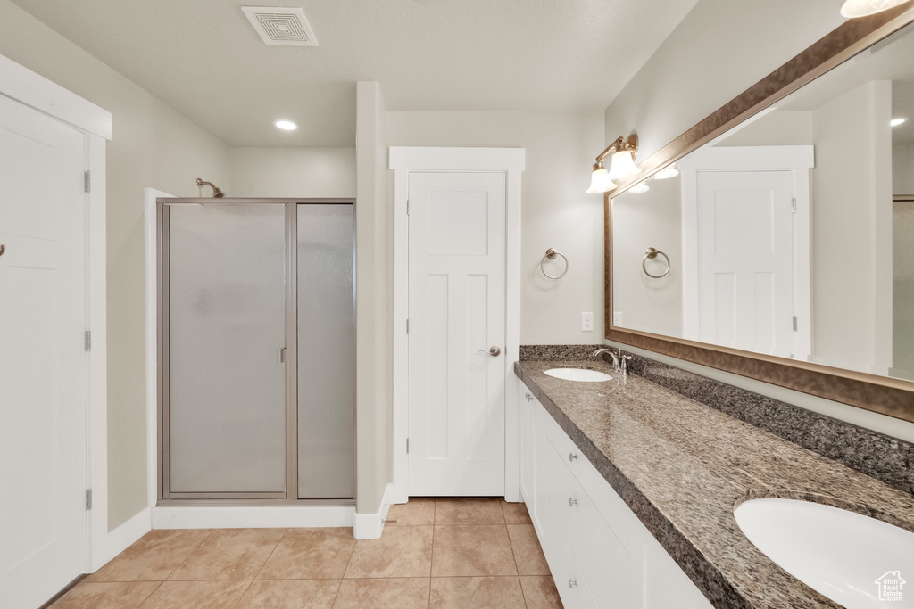 Bathroom with a stall shower, double vanity, tile patterned floors, and recessed lighting