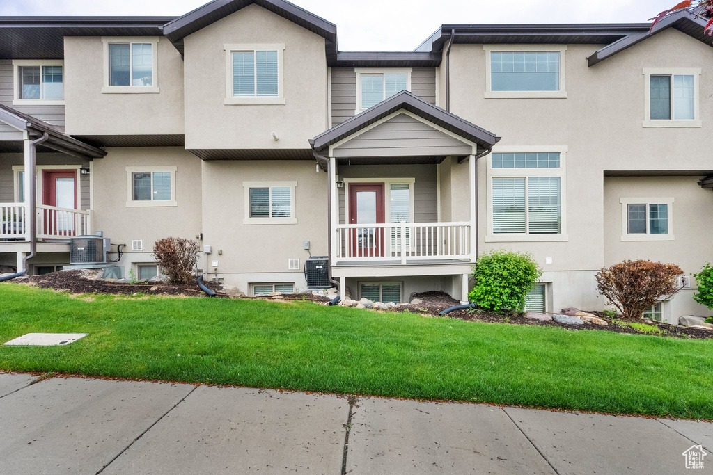 Back of property featuring stucco siding, central AC, and a lawn