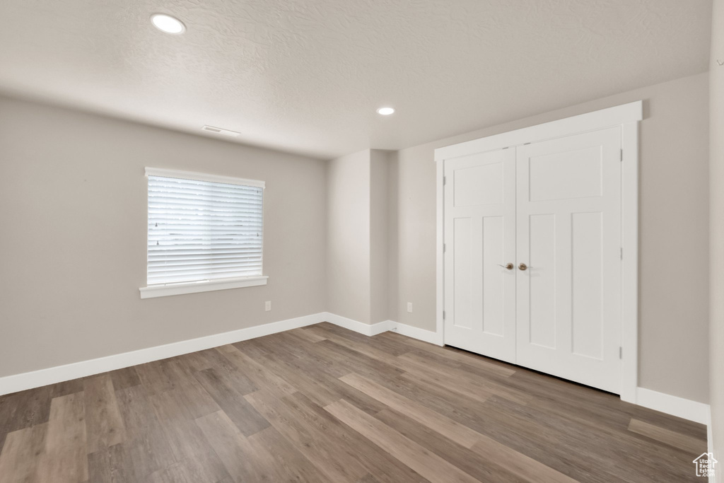 Unfurnished bedroom featuring baseboards, wood finished floors, recessed lighting, a closet, and a textured ceiling