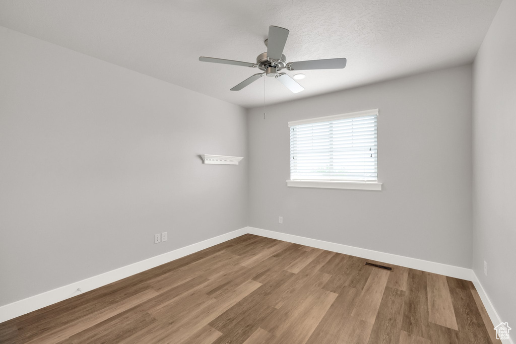 Unfurnished room with wood finished floors, a ceiling fan, and baseboards