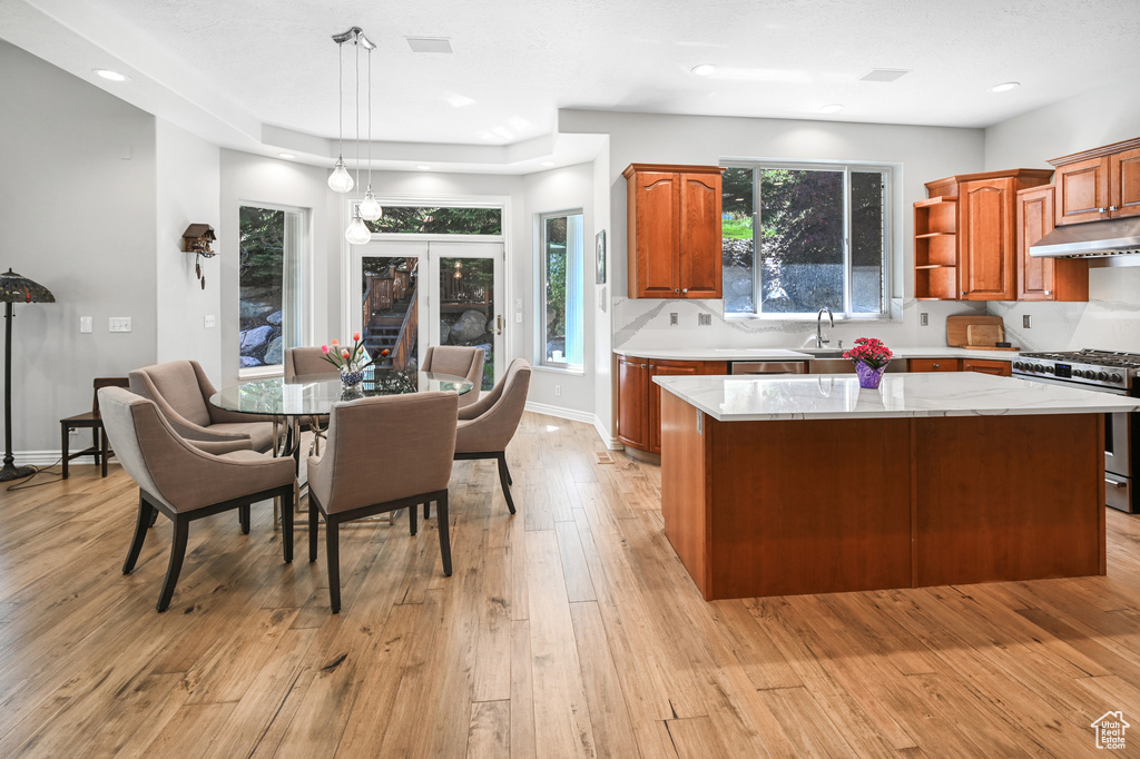Kitchen featuring under cabinet range hood, a sink, gas range, a kitchen island, and light countertops