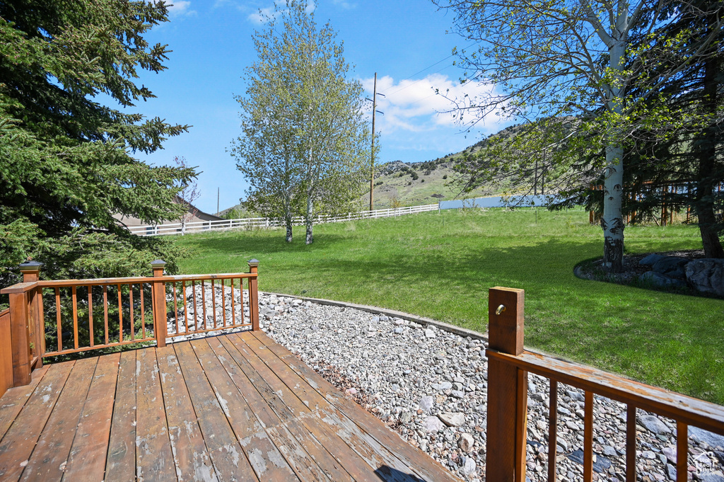 Wooden deck with a yard, a mountain view, and fence