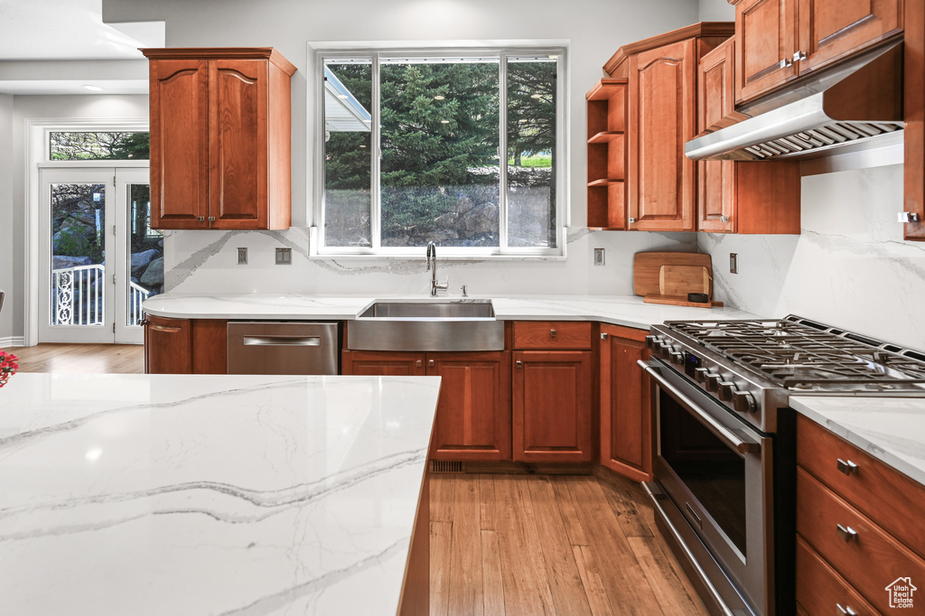 Kitchen with under cabinet range hood, stainless steel appliances, a sink, and light wood-style flooring