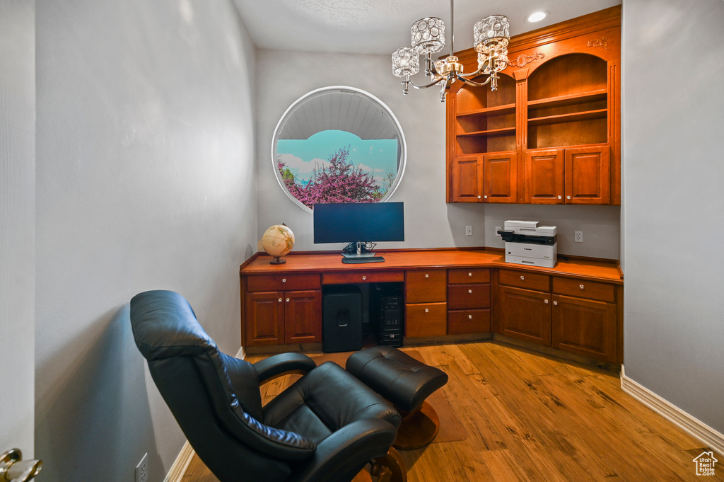 Office space featuring an inviting chandelier, light wood-type flooring, and baseboards