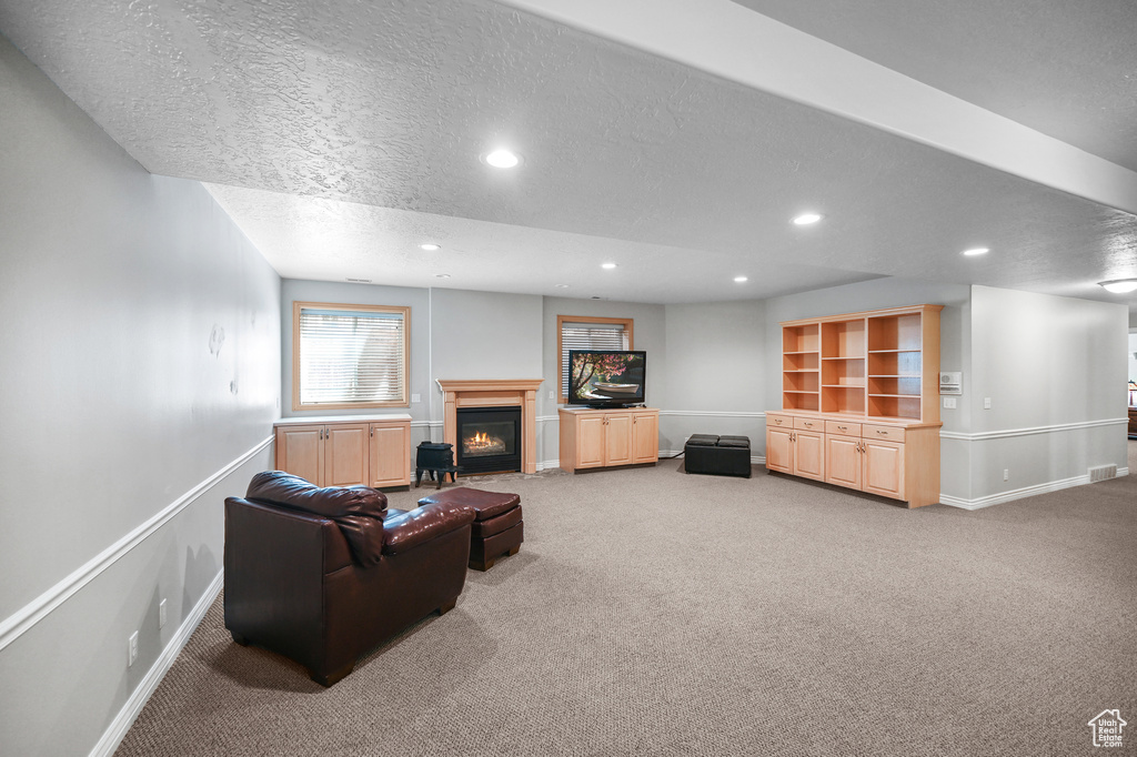 Living area featuring baseboards, a warm lit fireplace, and carpet floors
