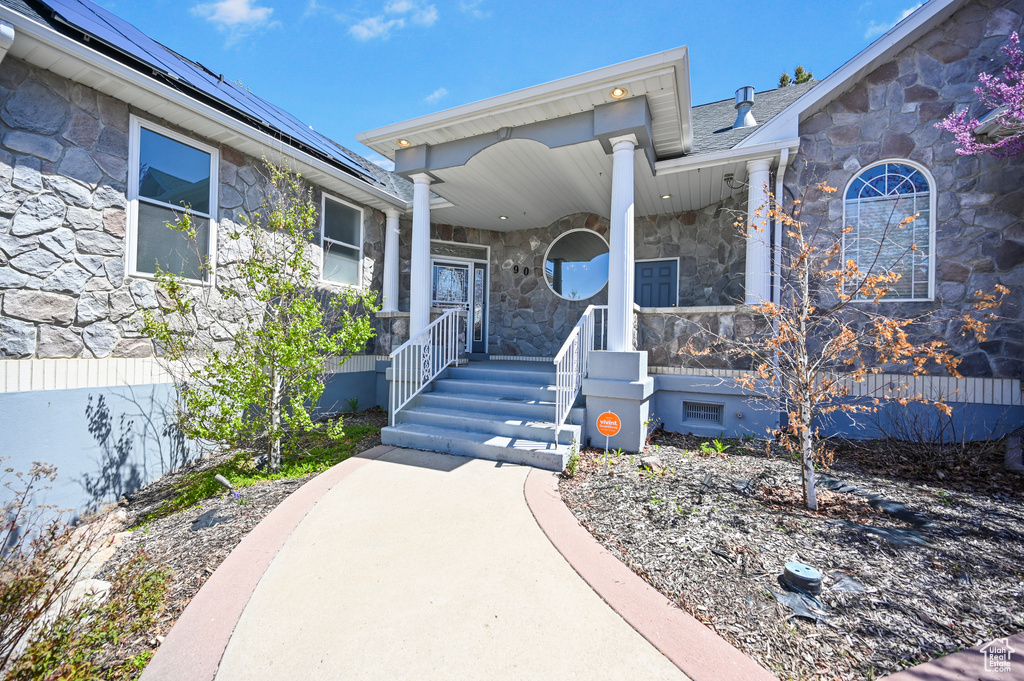 View of front facade featuring a porch, solar panels, and stone siding