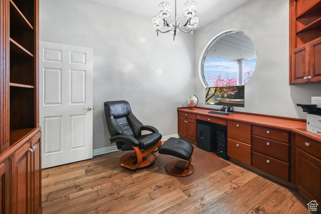 Home office featuring light wood-style floors and a notable chandelier