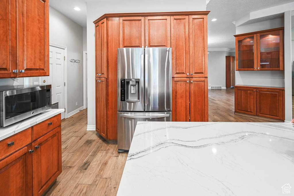 Kitchen with stainless steel appliances, baseboards, light wood-style floors, light stone counters, and recessed lighting