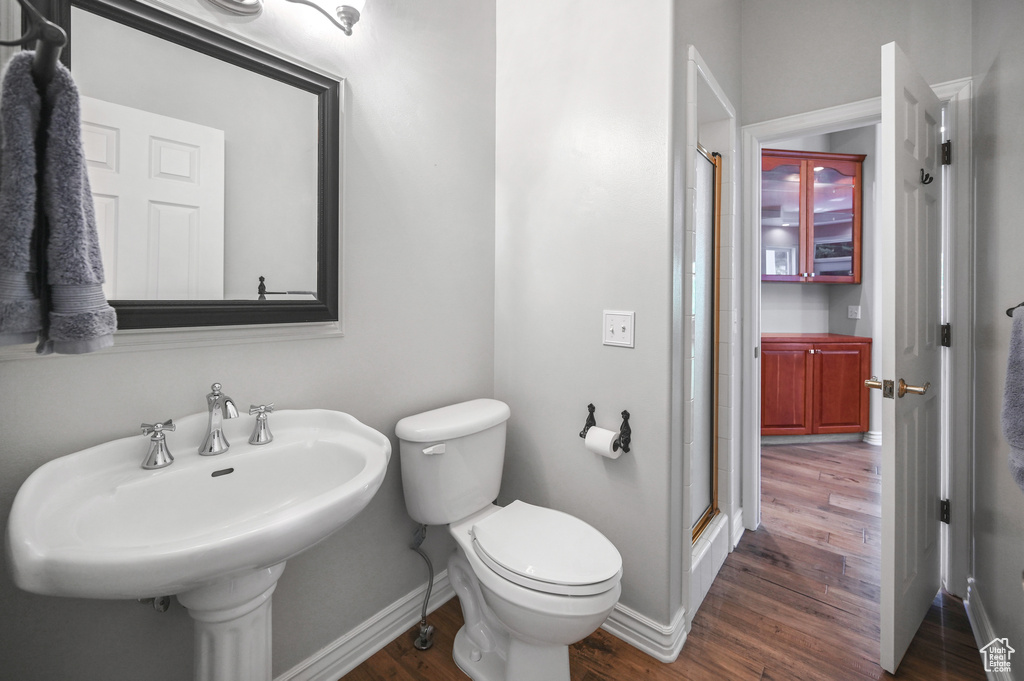 Full bathroom with a sink, toilet, wood finished floors, a shower stall, and baseboards