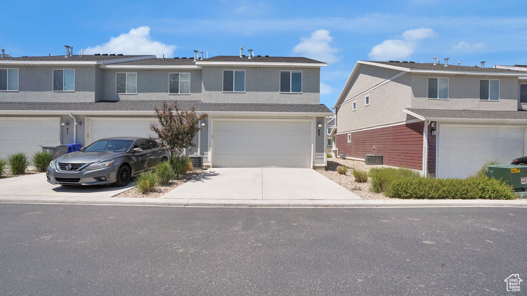 Multi unit property with an attached garage, concrete driveway, and stucco siding