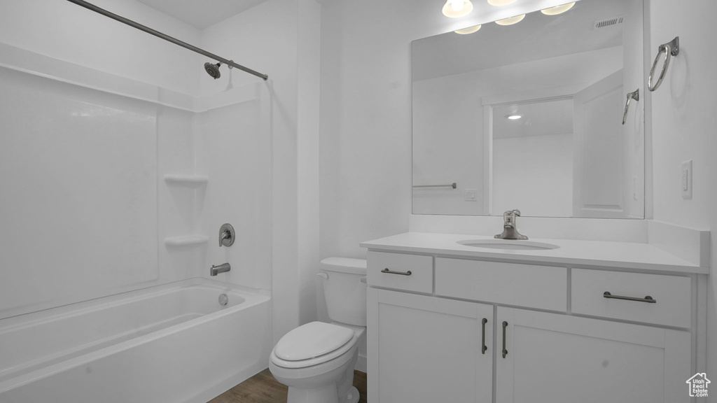 Full bathroom with vanity, toilet, wood finished floors, and washtub / shower combination