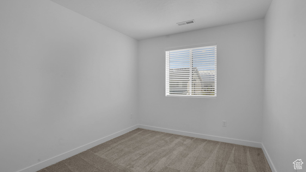 Unfurnished room featuring baseboards and light carpet