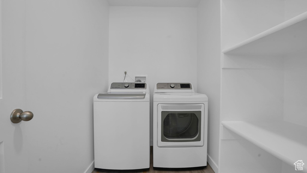 Washroom featuring separate washer and dryer, baseboards, and wood finished floors