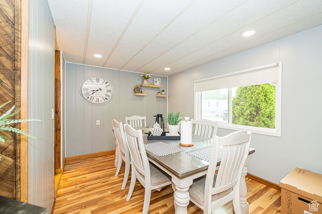 Dining space with light wood finished floors, recessed lighting, baseboards, and a textured ceiling