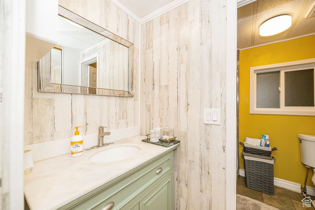 Bathroom featuring toilet, vanity, ornamental molding, and baseboards